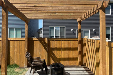 Photo of a mid-sized backyard wood fence landscaping in Edmonton with a pergola.