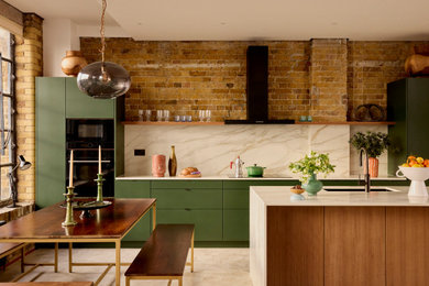 Inspiration for an industrial galley kitchen in London with a submerged sink, flat-panel cabinets, green cabinets, white splashback, stone slab splashback, black appliances, an island, beige floors and white worktops.