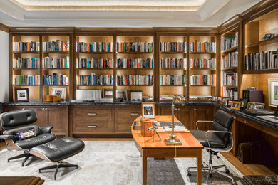 Large elegant freestanding desk medium tone wood floor and brown floor home office library photo in Boston with gray walls