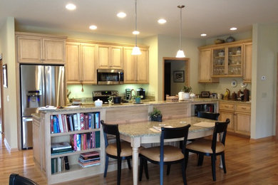 Example of a classic light wood floor eat-in kitchen design in Chicago with raised-panel cabinets, granite countertops, stainless steel appliances and an island