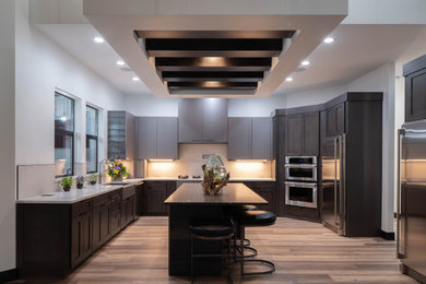 Example of a huge trendy u-shaped medium tone wood floor and brown floor enclosed kitchen design in Other with an undermount sink, flat-panel cabinets, gray cabinets, marble countertops, beige backsplash, ceramic backsplash, stainless steel appliances, two islands and yellow countertops