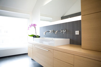 Kleines Modernes Badezimmer En Suite mit hellbraunen Holzschränken, Einbaubadewanne, bodengleicher Dusche, Wandtoilette, grauen Fliesen, Keramikfliesen, weißer Wandfarbe, Porzellan-Bodenfliesen, Aufsatzwaschbecken, Waschtisch aus Holz, grauem Boden, offener Dusche und brauner Waschtischplatte in Sonstige