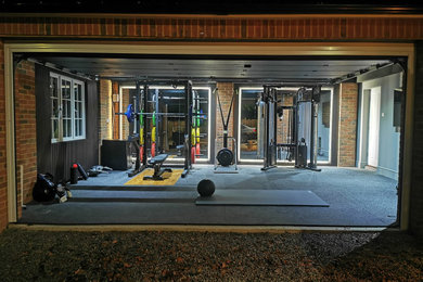 Design ideas for a medium sized modern home weight room in London with black walls, black floors and feature lighting.