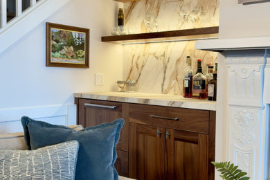 Inspiration for a small timeless single-wall medium tone wood floor and brown floor dry bar remodel in Other with no sink, shaker cabinets, medium tone wood cabinets, solid surface countertops, beige backsplash, stone slab backsplash and beige countertops