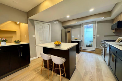 Mid-sized transitional light wood floor eat-in kitchen photo in Boston with an undermount sink, shaker cabinets, black cabinets, quartz countertops, stainless steel appliances, an island and white countertops