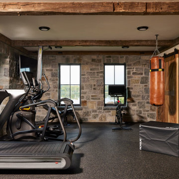 Hand Hewn Timbers and Weathered Antique Barn Door in Farmhouse Home Gym