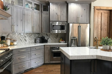 Mid-sized transitional u-shaped eat-in kitchen in Atlanta with an undermount sink, shaker cabinets, grey cabinets, quartzite benchtops, grey splashback, porcelain splashback, stainless steel appliances, medium hardwood floors, with island, brown floor and white benchtop.