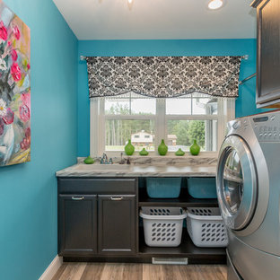 Classic l-shaped separated utility room in Other with a built-in sink, recessed-panel cabinets, black cabinets, blue walls, light hardwood flooring, a side by side washer and dryer, beige floors and grey worktops.