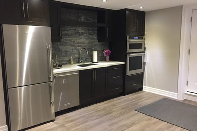 Eat-in kitchen - mid-sized transitional single-wall light wood floor and brown floor eat-in kitchen idea in Toronto with an undermount sink, shaker cabinets, dark wood cabinets, gray backsplash, stone tile backsplash, stainless steel appliances and no island