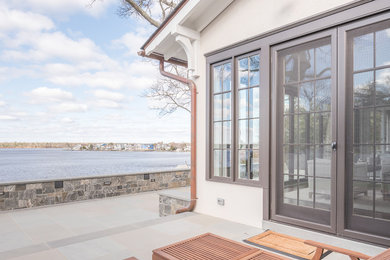 Large elegant concrete back porch photo in New York with a roof extension
