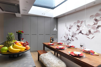 This is an example of a small contemporary kitchen/dining combo in London with medium hardwood floors, a standard fireplace and multi-coloured walls.