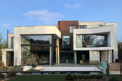 This is an example of an expansive contemporary three-storey house exterior in Surrey with metal siding, a flat roof and a mixed roof.