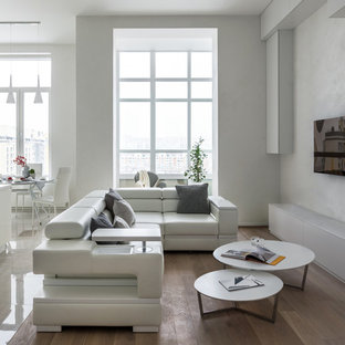 Свежая идея для дизайна: открытая, парадная гостиная комната среднего размера в современном стиле с паркетным полом среднего тона, телевизором на стене, белыми стенами и коричневым полом без камина - отличное фото интерьера