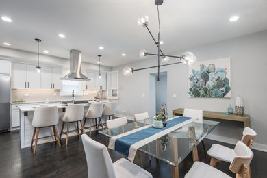 Example of a mid-sized trendy single-wall dark wood floor and brown floor eat-in kitchen design in Chicago with an undermount sink, shaker cabinets, white cabinets, quartz countertops, gray backsplash, ceramic backsplash, stainless steel appliances, an island and white countertops