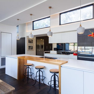 Photo of a contemporary galley eat-in kitchen in Melbourne with a double-bowl sink, flat-panel cabinets, white cabinets, wood benchtops, dark hardwood floors, with island, brown floor and beige benchtop.