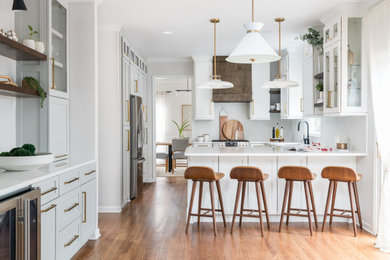 Mid-sized transitional u-shaped medium tone wood floor and brown floor kitchen pantry photo in Atlanta with an undermount sink, shaker cabinets, white cabinets, quartz countertops, gray backsplash, ceramic backsplash, an island and gray countertops