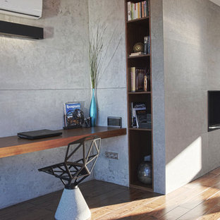 This is an example of a small contemporary home office in Other with grey walls, dark hardwood floors, a ribbon fireplace, a tile fireplace surround, a built-in desk and brown floor.