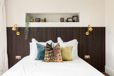 Ejemplo de habitación de invitados actual de tamaño medio con paredes blancas, suelo de madera en tonos medios y suelo marrón