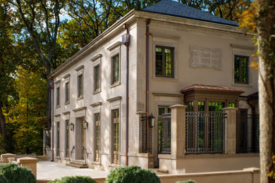Example of a large classic beige two-story stone house exterior design in DC Metro with a hip roof and a tile roof