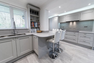Design ideas for an expansive traditional u-shaped open plan kitchen in Hertfordshire with an undermount sink, shaker cabinets, grey cabinets, quartzite benchtops, grey splashback, ceramic splashback, panelled appliances, painted wood floors, a peninsula and grey floor.