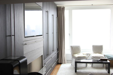 Example of a mid-sized minimalist formal and enclosed light wood floor living room design in New York with white walls, a standard fireplace, a wood fireplace surround and a media wall