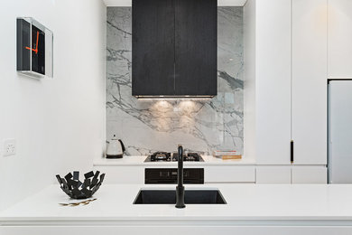 Photo of a small modern separate kitchen in Melbourne with an undermount sink, white cabinets, quartz benchtops, multi-coloured splashback, marble splashback, black appliances, light hardwood floors and with island.