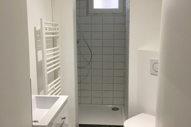 Cette photo montre une petite douche en alcôve principale tendance avec un placard à porte plane, des portes de placard blanches, WC suspendus, un carrelage blanc, des carreaux de céramique, un mur blanc, un sol en carrelage de céramique, une vasque, un plan de toilette en bois, un sol noir, aucune cabine et un plan de toilette blanc.