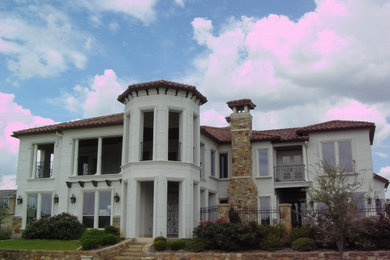 This is an example of a large transitional one-storey white house exterior in Dallas with a hip roof, stone veneer and a tile roof.