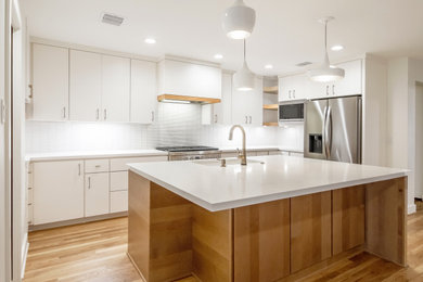 Kitchen - small transitional u-shaped medium tone wood floor kitchen idea in Houston with a single-bowl sink, flat-panel cabinets, medium tone wood cabinets, quartz countertops, white backsplash, mosaic tile backsplash, stainless steel appliances, an island and white countertops