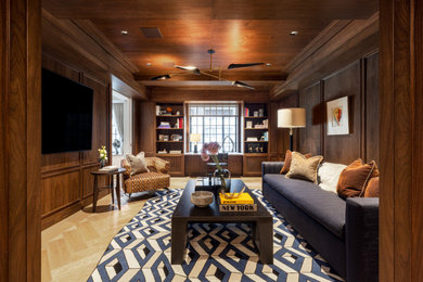 Ejemplo de sala de estar cerrada clásica renovada grande con paredes marrones, suelo de madera clara, televisor colgado en la pared, suelo beige, madera y panelado