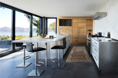 Eat-in kitchen - large contemporary l-shaped porcelain tile eat-in kitchen idea in New York with flat-panel cabinets, light wood cabinets, marble countertops, white backsplash, marble backsplash, paneled appliances, an island and white countertops
