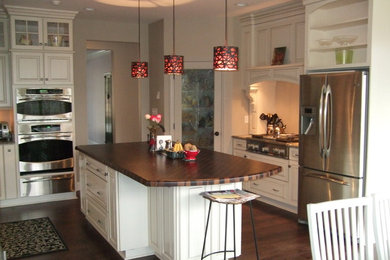 Kitchen pantry - large traditional u-shaped kitchen pantry idea in Other with raised-panel cabinets, white cabinets, wood countertops, stainless steel appliances and an island
