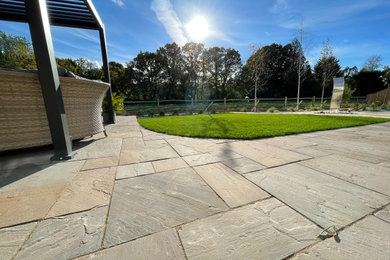 Inspiration for a large modern back full sun garden for summer in Dorset with a pathway, natural stone paving and a wood fence.