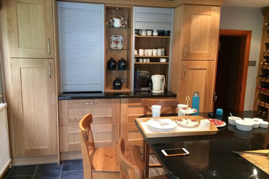 Photo of a medium sized modern single-wall kitchen/diner in Hertfordshire with shaker cabinets, medium wood cabinets, granite worktops, porcelain flooring, an island and grey floors.