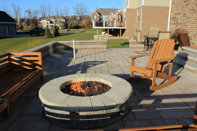 Example of a minimalist backyard concrete paver patio design in Detroit with a fire pit