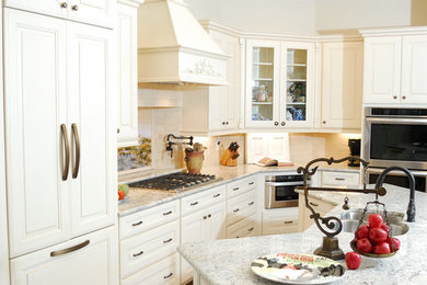 Large transitional l-shaped medium tone wood floor and brown floor open concept kitchen photo in Houston with raised-panel cabinets, white cabinets, granite countertops, an island, gray countertops, a double-bowl sink, beige backsplash, stone tile backsplash and stainless steel appliances