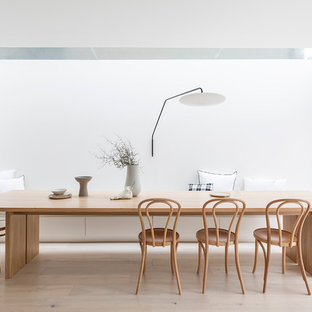 Modelo de comedor moderno con paredes blancas, suelo de madera clara y suelo beige