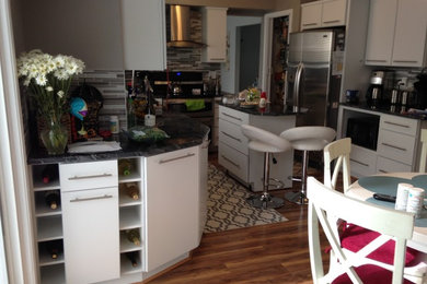 Kitchen photo in Detroit with a farmhouse sink, flat-panel cabinets, white cabinets, stainless steel appliances and an island