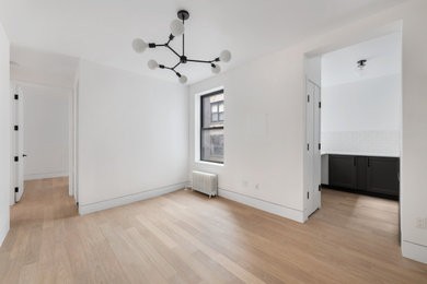 Example of a large open concept light wood floor and beige floor living room design in New York with white walls