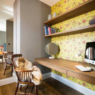 Inredning av ett klassiskt hemmabibliotek, med flerfärgade väggar, mellanmörkt trägolv och ett inbyggt skrivbord