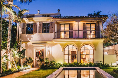 Example of a large island style beige two-story stucco exterior home design in Miami with a tile roof