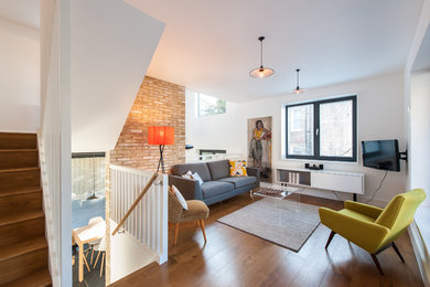 Photo of a contemporary formal living room in London with white walls, medium hardwood flooring and a wall mounted tv.