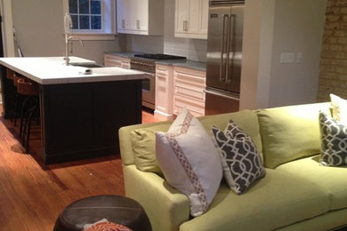 Mid-sized trendy single-wall light wood floor eat-in kitchen photo in Charleston with a farmhouse sink, shaker cabinets, white cabinets, white backsplash, subway tile backsplash, stainless steel appliances and an island