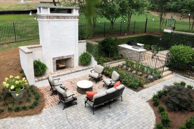 Elegant backyard brick patio photo with a fireplace and no cover