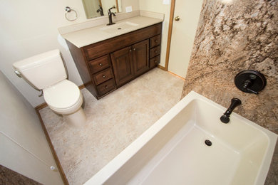 Inspiration for a mid-sized traditional master bathroom in Grand Rapids with raised-panel cabinets, dark wood cabinets, an alcove tub, a shower/bathtub combo, a one-piece toilet, beige tile, stone slab, beige walls, limestone floors, an integrated sink, beige floor and a shower curtain.