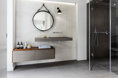 Großes Modernes Badezimmer En Suite mit flächenbündigen Schrankfronten, grauen Schränken, bodengleicher Dusche, Wandtoilette mit Spülkasten, beigen Fliesen, Kalkfliesen, weißer Wandfarbe, Kalkstein, integriertem Waschbecken, grauem Boden und grauer Waschtischplatte in Sonstige