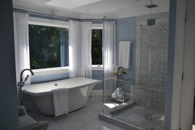 おしゃれなマスターバスルーム (置き型浴槽、コーナー設置型シャワー、グレーのタイル、青い壁、大理石の床、オーバーカウンターシンク、御影石の洗面台) の写真