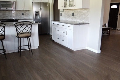 Eat-in kitchen - mid-sized l-shaped dark wood floor eat-in kitchen idea in Phoenix with white backsplash and an island