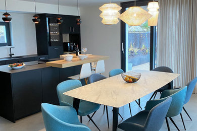 Cette image montre une salle à manger ouverte sur la cuisine design avec un mur bleu et un sol gris.