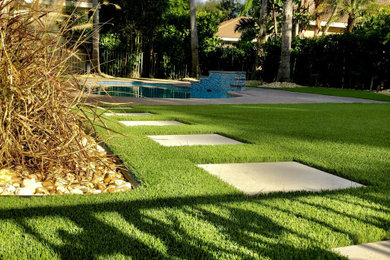 Modelo de piscina de estilo americano de tamaño medio tipo riñón en patio trasero con paisajismo de piscina y adoquines de hormigón